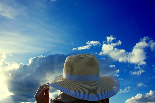 Vista posteriore di una donna che indossa un cappello contro il cielo blu