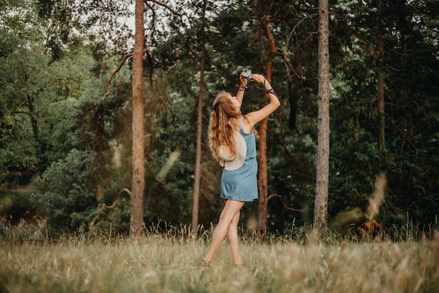 Vista posteriore di una donna che scatta una foto in piedi nella foresta