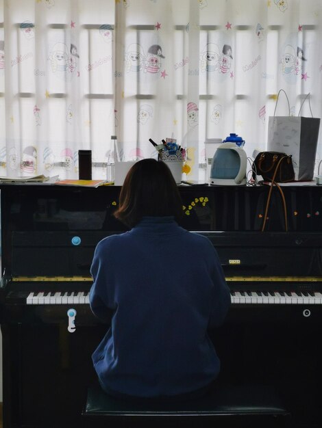 Vista posteriore di una donna che suona il pianoforte