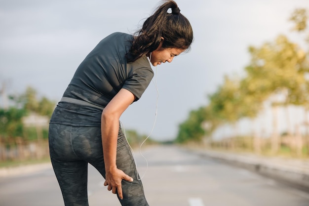 Vista posteriore di una donna con dolore alla gamba in piedi sulla strada