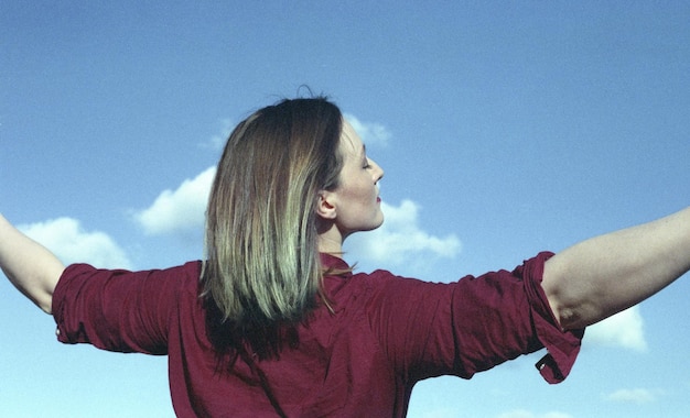 Vista posteriore di una donna con le braccia stese contro il cielo