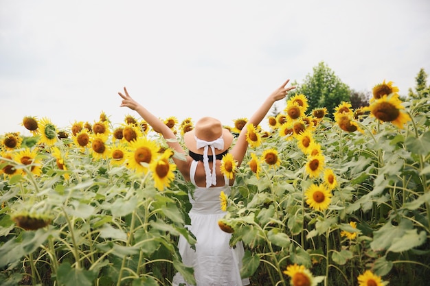 Vista posteriore di una donna con le braccia tese in piedi sul campo di girasole