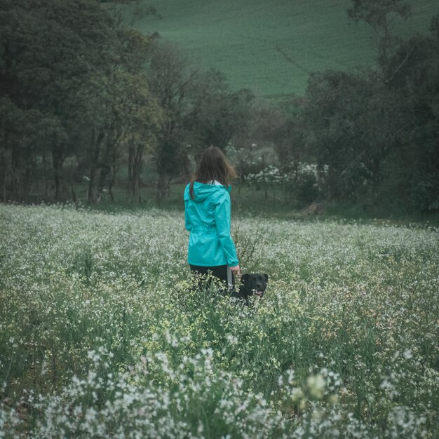 Vista posteriore di una donna con un cane in piedi tra le piante sul campo