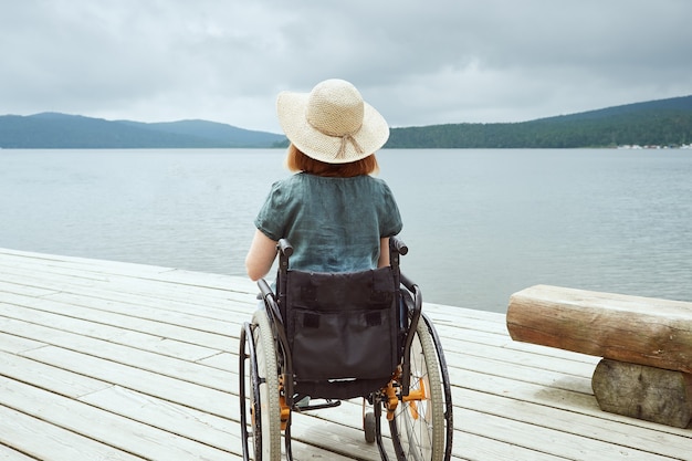 Vista posteriore di una donna disabile che si gode la splendida vista del paesaggio marino