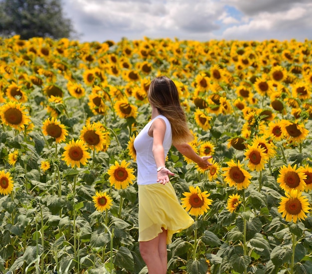 Vista posteriore di una donna in piedi in un campo di girasoli