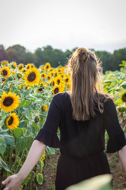 Vista posteriore di una donna in piedi su un campo di girasoli