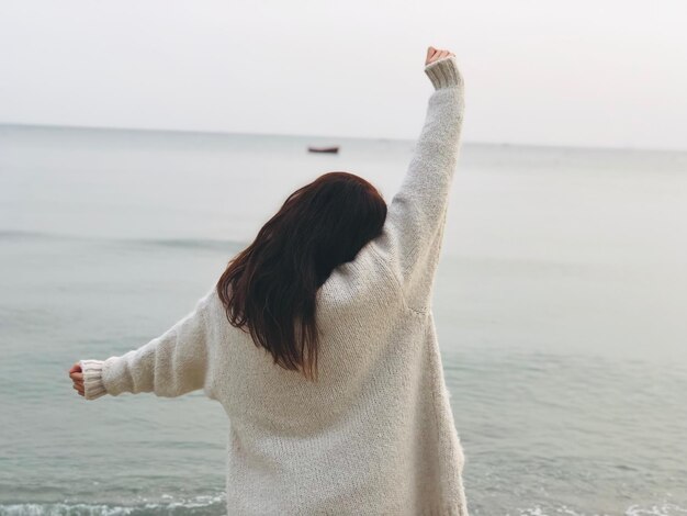 Vista posteriore di una donna in piedi sulla spiaggia durante il tramonto