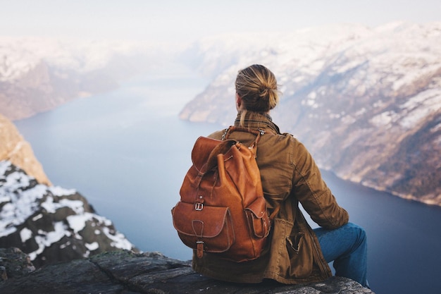 Vista posteriore di una donna seduta su una scogliera di fronte al fiume