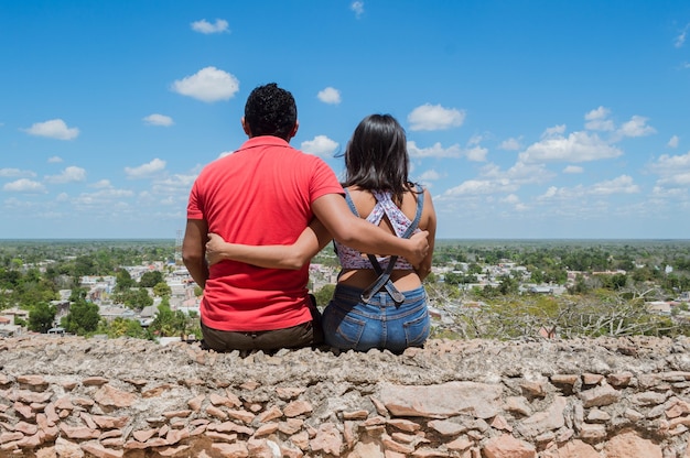 Vista posteriore di una giovane coppia che guarda la periferia della città dalle alture di Ermita de Tekax