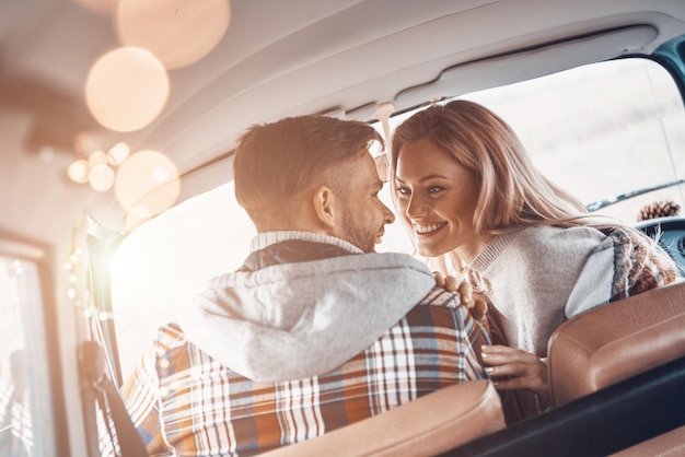 Vista posteriore di una giovane e bella coppia che si gode il viaggio insieme mentre è seduto sui sedili anteriori del minivan