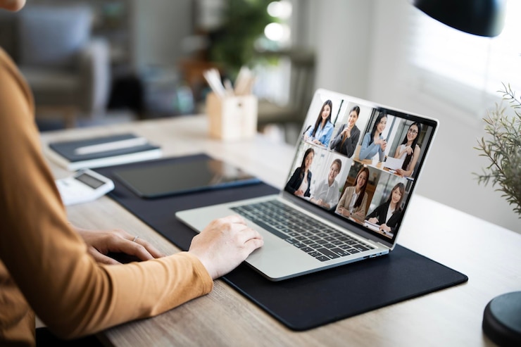Foto vista posteriore di una impiegata che parla, parla su video con i colleghi online, una lavoratrice che ha una conferenza di gruppo con i suoi colleghi su un portatile moderno a casa