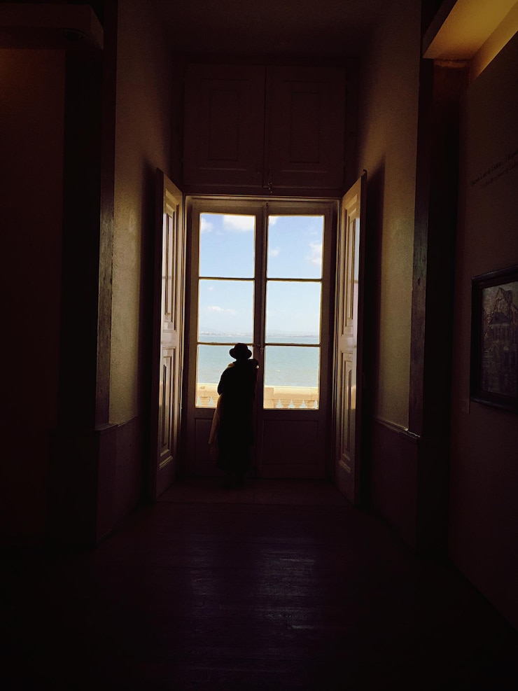 Foto vista posteriore di una persona in piedi vicino alla finestra a casa