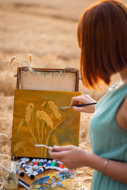 Vista posteriore di una pittrice raffigurante spighette di grano su tela