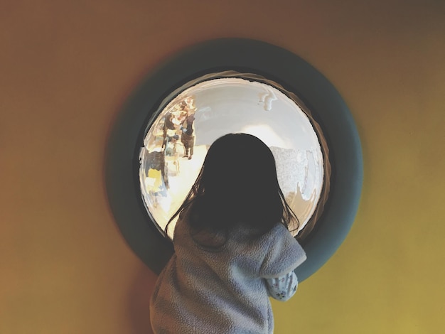 Vista posteriore di una ragazza che guarda attraverso una finestra di vetro
