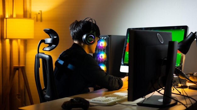 Vista posteriore Giocatore maschio asiatico professionista felice che gioca ai videogiochi sul computer PC personale Gioco online di Esport