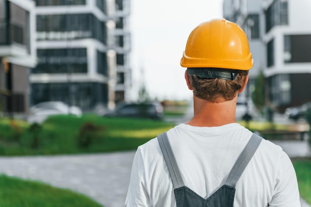 Vista posteriore Giovane che lavora in uniforme alla costruzione durante il giorno