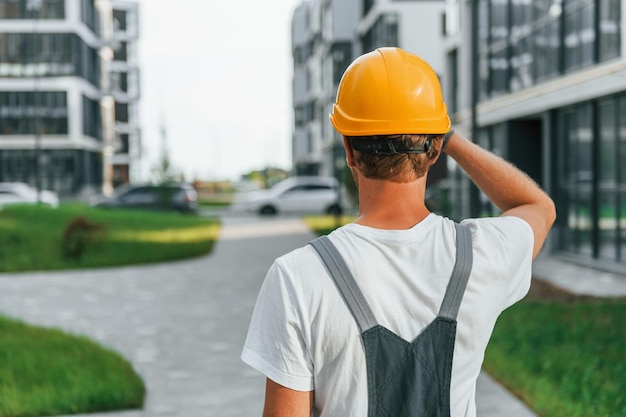 Vista posteriore Giovane che lavora in uniforme alla costruzione durante il giorno