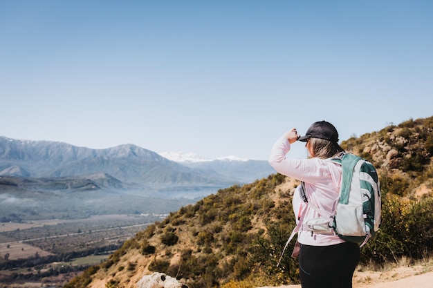 Vista posteriore giovane donna latina plus size con zaino, contemplando la vista dalla cima di una collina