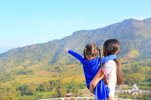 Vista posteriore Madre asiatica portando la figlia sul balcone a una collina e sottolineando che per vedere.