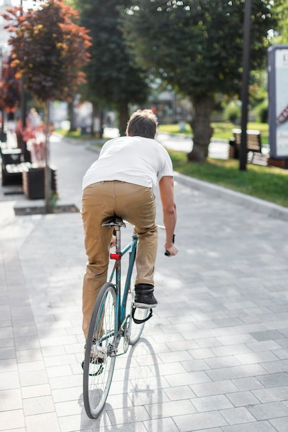 Vista posteriore maschile casual in bicicletta all'aperto