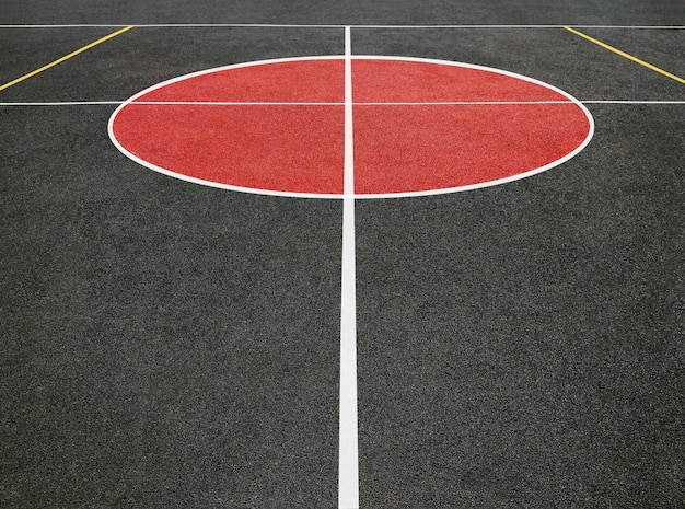 Vista prospettica del cerchio centrale del campo sportivo con linee bianche. Campo da gioco nero e rosso