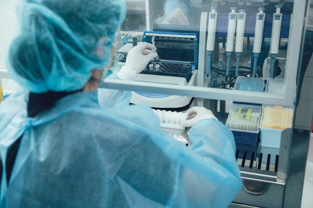 Vista rara di un lavoratore di laboratorio che tiene microtubi e li mette in un termostato per un lungo processo di incubazione