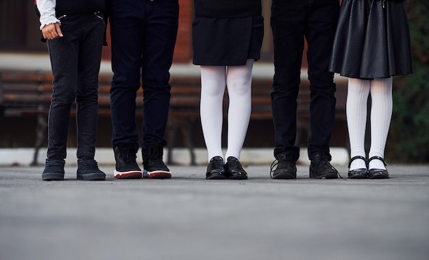 Vista ravvicinata dei bambini in uniforme scolastica che è insieme all'aperto vicino all'edificio scolastico.