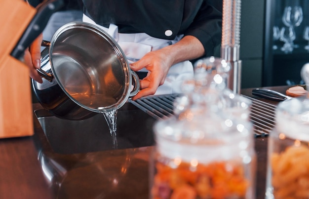 Vista ravvicinata del giovane cuoco professionista in uniforme che lavora in cucina