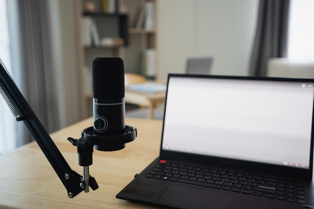 Vista ravvicinata del posto di lavoro con portatile e microfono a schermo bianco per lo streaming o il gioco notebook e decorazione nella stanza dell'ufficio a casa Lavoro a casa posto nel concetto del salotto