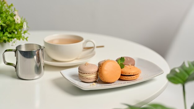 Vista ravvicinata del tavolino da caffè con macarons colorati francesi e tazza di tè nel soggiorno