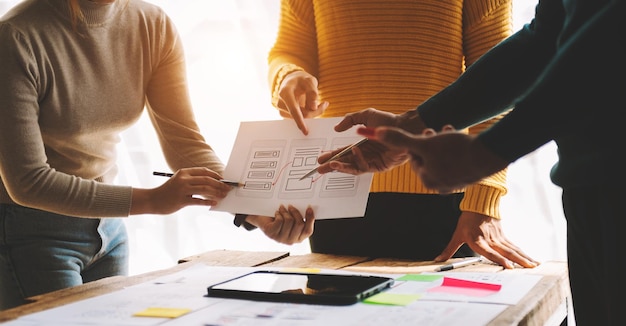 Vista ravvicinata del team di sviluppatori dell'interfaccia utente che fa brainstorming sul proprio progetto con smartphone portatile e tablet digitale