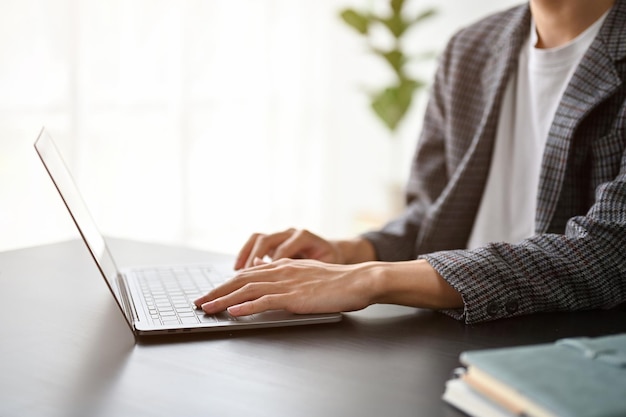 Vista ravvicinata dell'uomo d'affari che digita sul computer portatile mentre si lavora nella stanza dell'ufficio