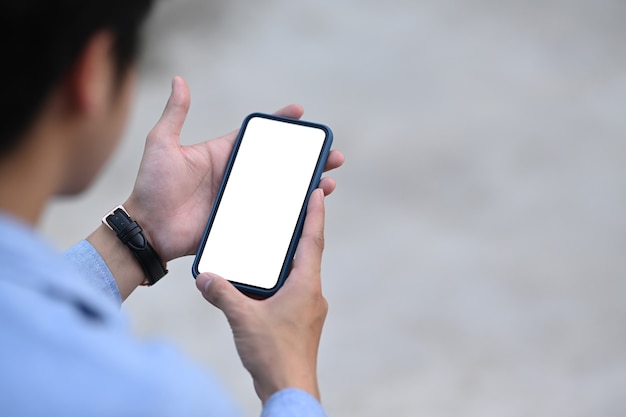 Vista ravvicinata dell'uomo d'affari utilizzando il telefono cellulare con schermo vuoto all'aperto.