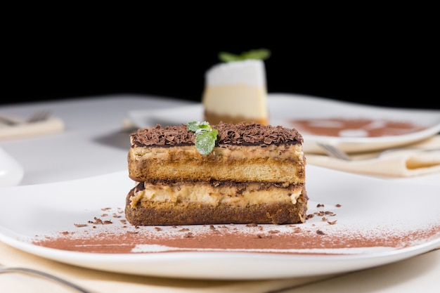 Vista ravvicinata della fetta gourmet di deliziosa torta al cioccolato su piastra bianca con polvere di cioccolato. Servito sul tavolo per l'ospite.