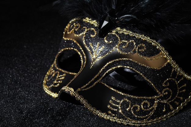 Vista ravvicinata della maschera d'oro di Masquerade con piume su sfondo nero