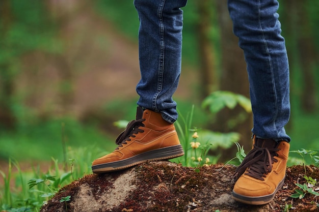 Vista ravvicinata delle gambe dell'uomo sulla roccia nella foresta Il viaggiatore fa una passeggiata