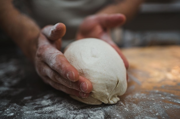 Vista ravvicinata delle mani che modellano la pasta di pane nella panetteria artigianale