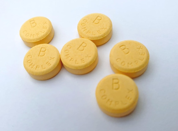 Vista ravvicinata delle pillole gialle complesse della vitamina B isolate su sfondo bianco Concetto di assistenza sanitaria