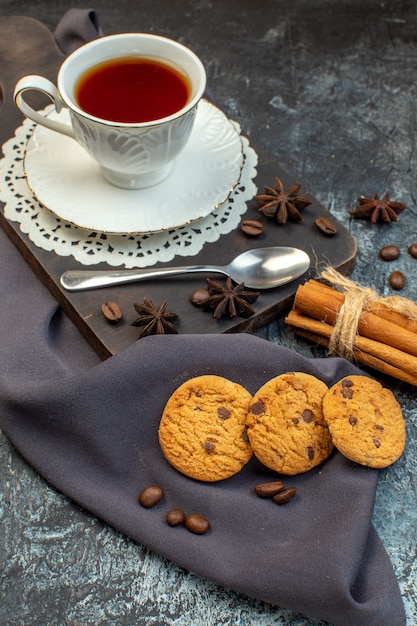 Vista ravvicinata di biscotti fatti in casa lime alla cannella e una tazza di tè su tagliere di legno chicchi di caffè su fondo di ghiaccio