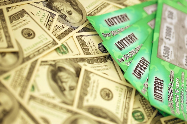 Vista ravvicinata di gratta e vinci della lotteria verde e banconote da un dollaro americano Molti hanno usato falsi biglietti della lotteria istantanea con risultati di gioco d'azzardo Dipendenza da gioco