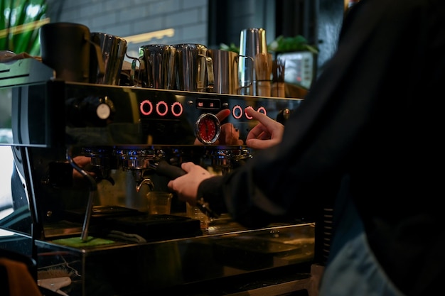 Vista ravvicinata di un barista maschio che prepara una tazza di caffè per il suo cliente in un moderno caffè buio