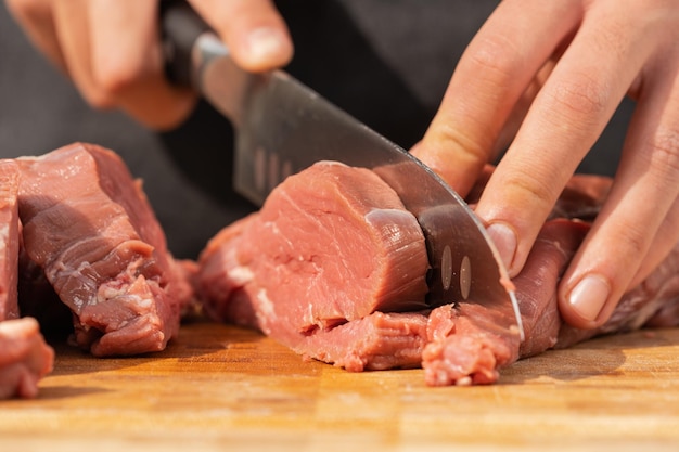 Vista ravvicinata di un uomo che taglia la carne su una tavola di legno