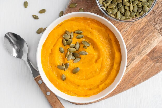 Vista ravvicinata di una cremosa zuppa di zucca vegetariana fatta di verdure in purè con semi secchi in ciotola