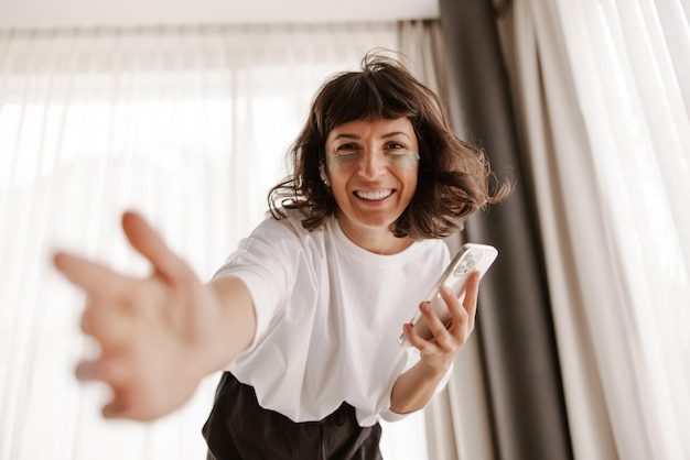 Vista ravvicinata di una donna sorridente con cerotti in gel verde guarda la fotocamera con il telefono