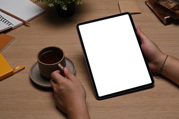 Vista ravvicinata giovane che tiene la tazza di caffè e utilizza la tavoletta digitale.