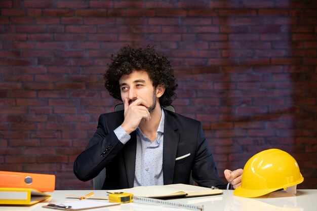 vista ravvicinata ingegnere maschio seduto dietro il suo posto di lavoro in tuta agenda lavoro piano costruttore architettura appaltatore aziendale lavoro