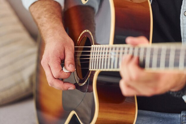 Vista ravvicinata L'uomo in abiti casual e con la chitarra acustica è al chiuso