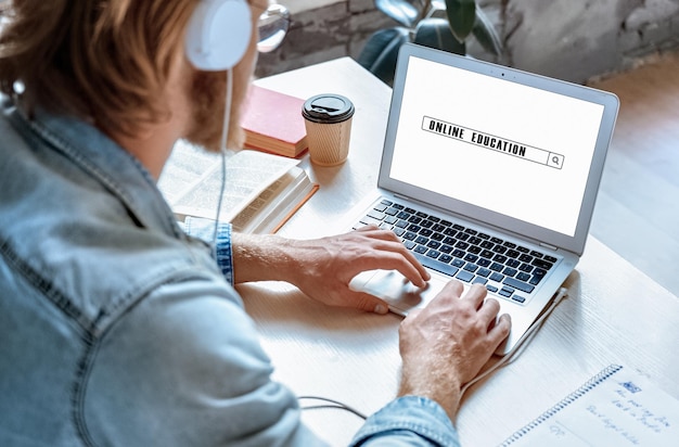 Vista ravvicinata sulla spalla dell'uomo che usa il laptop per cercare un corso di formazione online