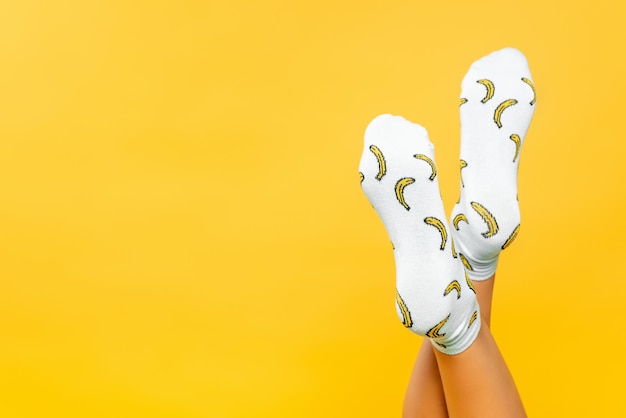 Vista ritagliata dei piedi della donna in calzini con stampa isolata su giallo