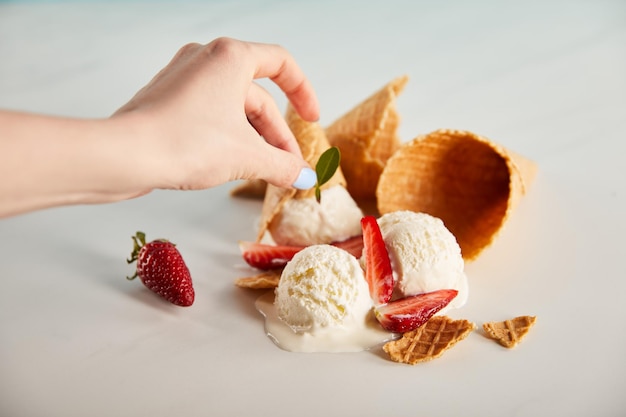 Vista ritagliata della donna che decora un delizioso gelato fondente con erbe su grigio